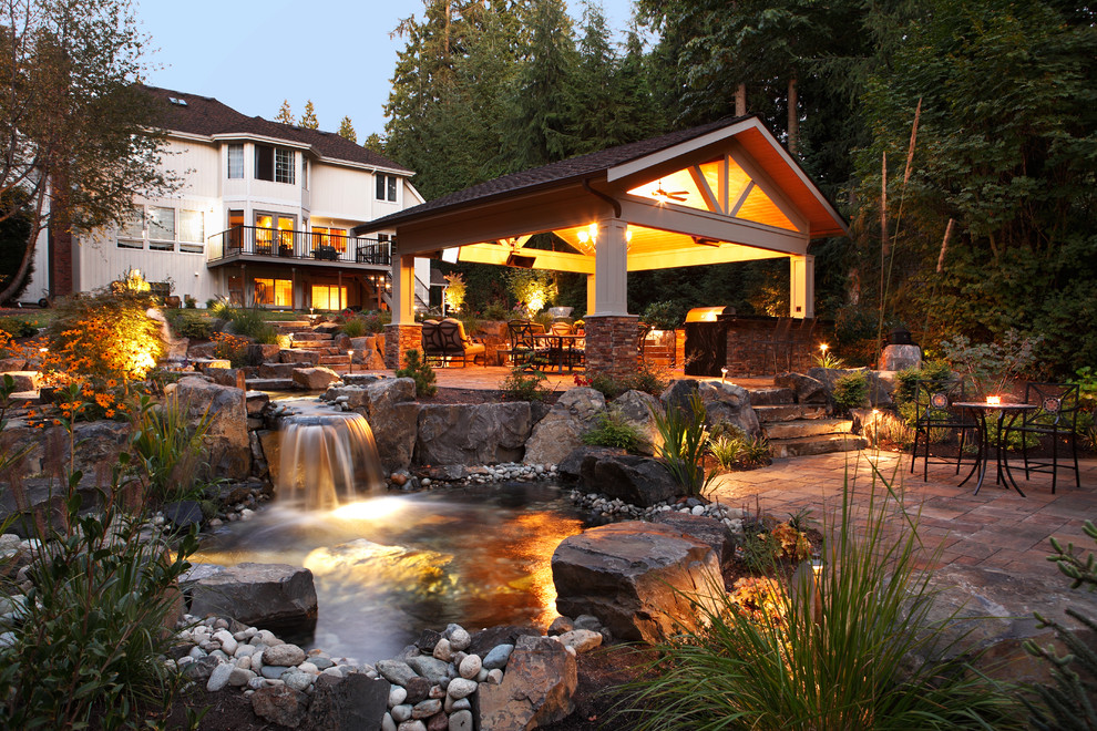 Example of a large classic backyard stone patio fountain design in Seattle with a gazebo