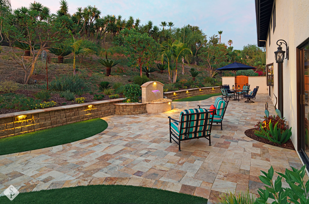 Immagine di un ampio patio o portico mediterraneo dietro casa con pavimentazioni in pietra naturale