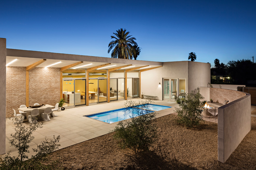Example of a trendy backyard patio design in Phoenix with a roof extension