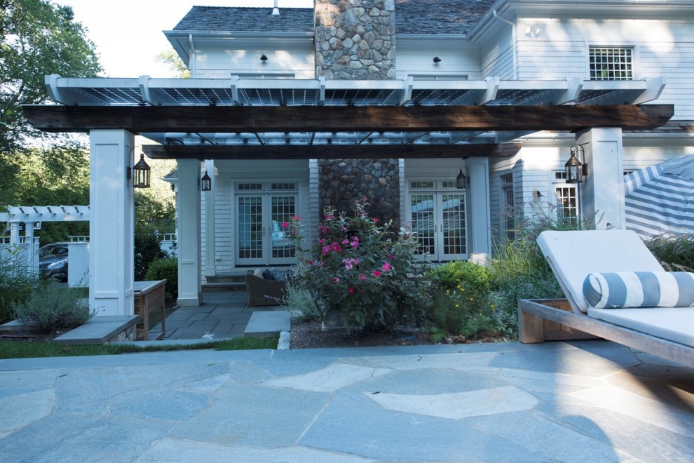 Immagine di un grande patio o portico stile marino dietro casa con pavimentazioni in pietra naturale e una pergola