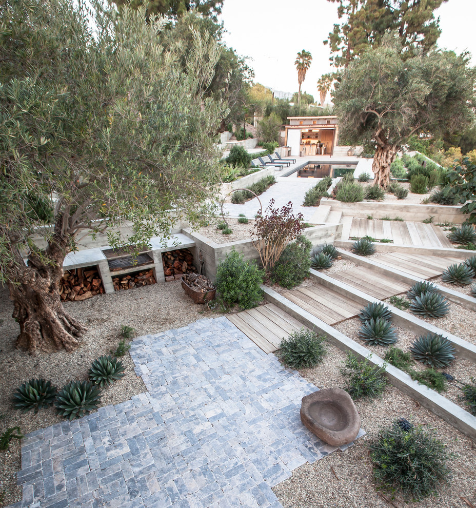 Inspiration for an expansive contemporary back patio in Los Angeles with natural stone paving and an outdoor kitchen.