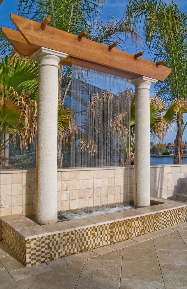Aménagement d'une terrasse arrière contemporaine de taille moyenne avec un point d'eau et des pavés en pierre naturelle.