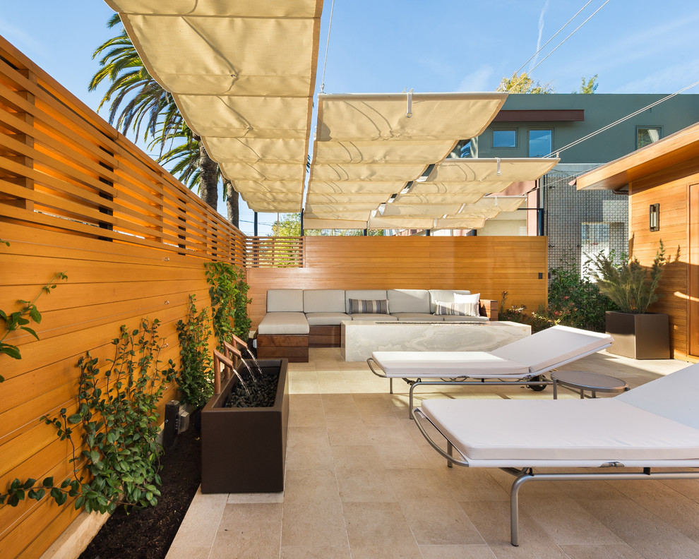 Inspiration for a medium sized modern patio in Los Angeles with a water feature, tiled flooring and an awning.