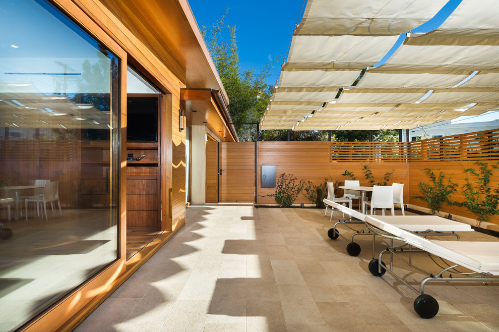 Imagen de patio minimalista de tamaño medio con suelo de baldosas y toldo
