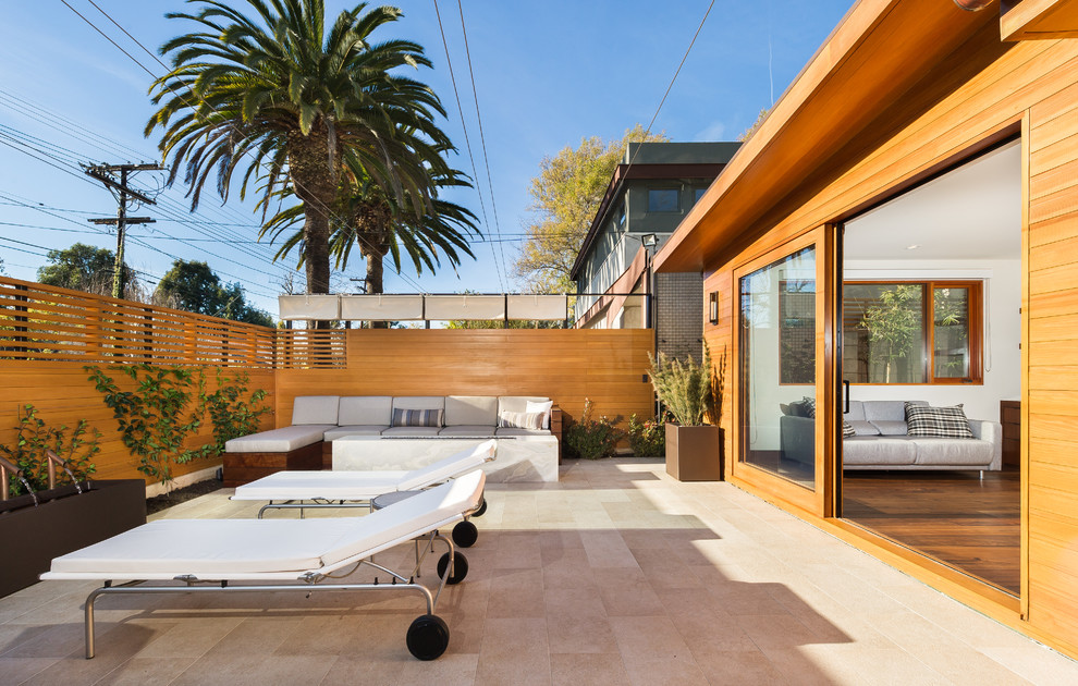 Foto de patio minimalista de tamaño medio en patio delantero con fuente, suelo de baldosas y toldo