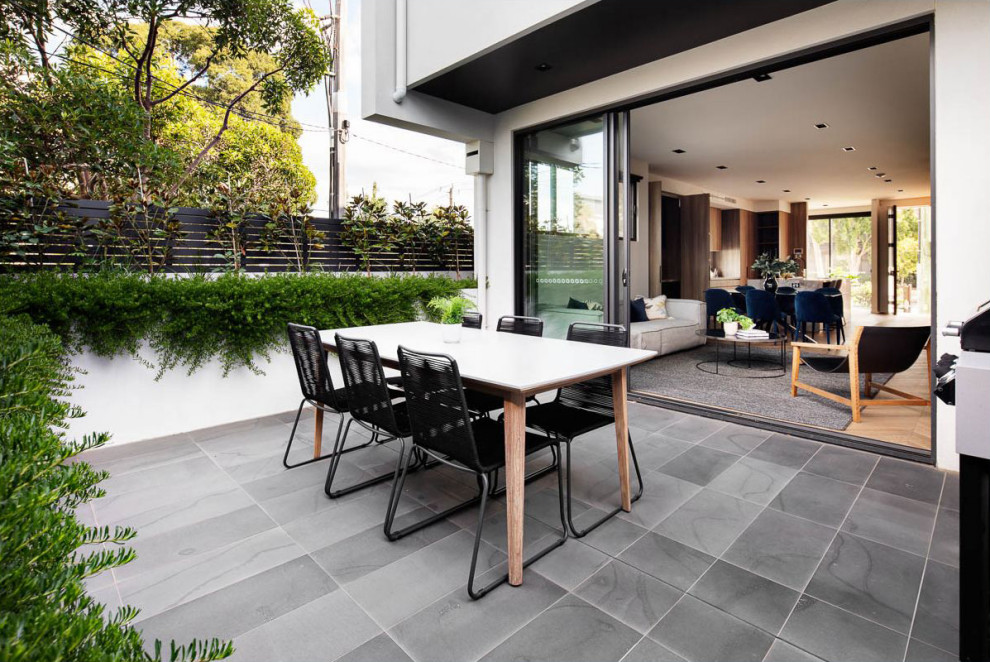 Ispirazione per un piccolo patio o portico minimalista dietro casa con piastrelle e nessuna copertura