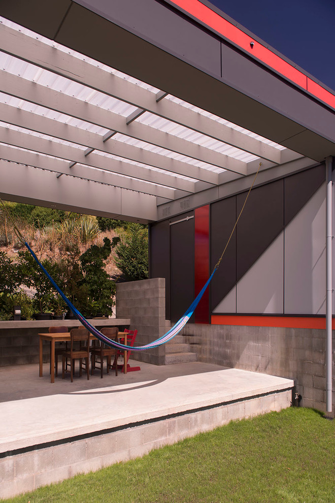 Idee per un patio o portico design con lastre di cemento e un tetto a sbalzo