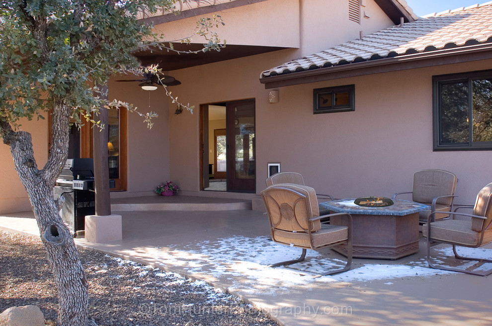 Foto di un grande patio o portico stile americano dietro casa con un focolare, lastre di cemento e un tetto a sbalzo