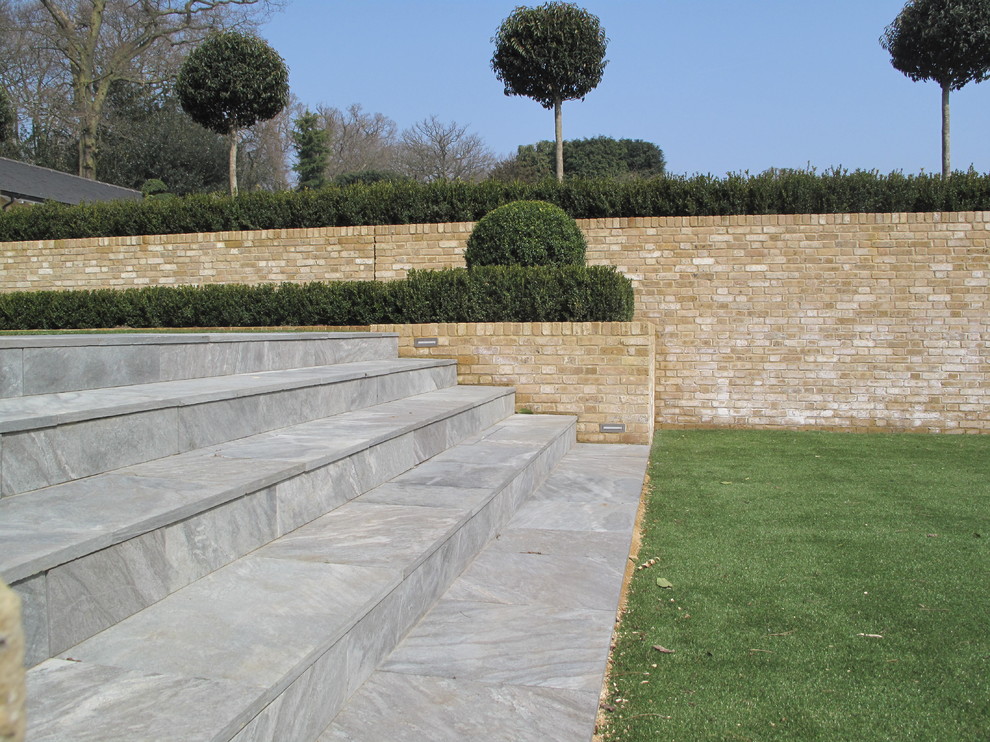This is an example of a large modern back patio in Essex with natural stone paving.