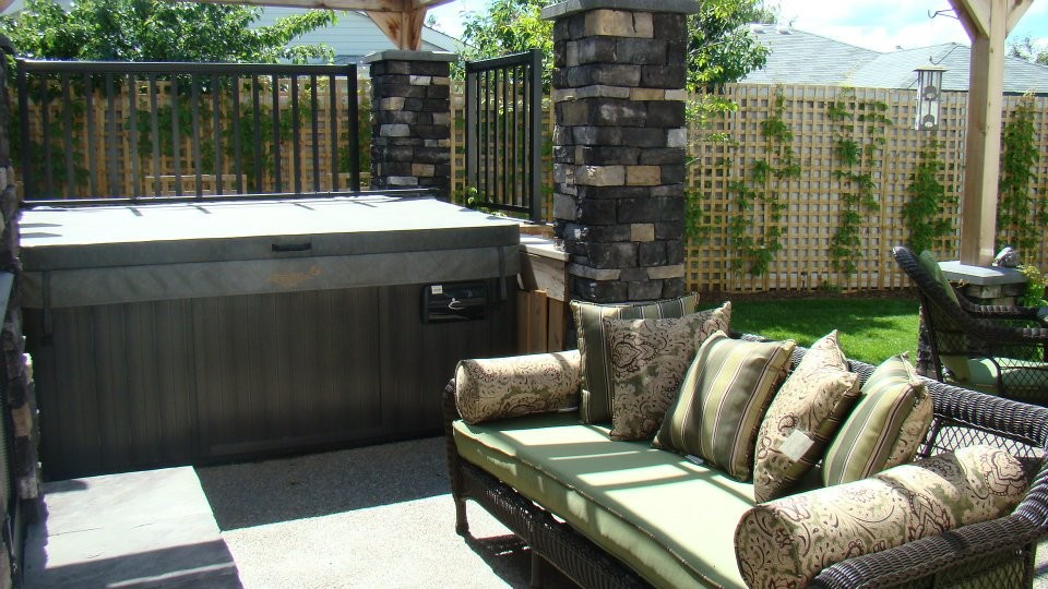 Medium sized traditional back patio in Calgary with a water feature and concrete slabs.