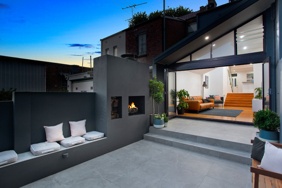 Idee per un patio o portico minimalista in cortile con un focolare e piastrelle