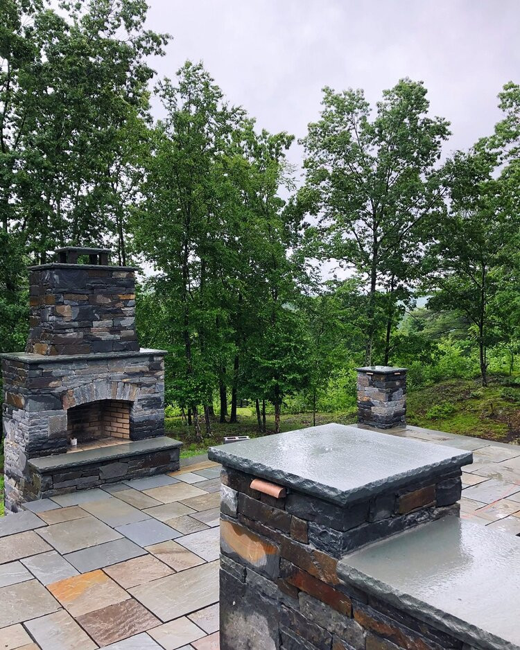 Imagen de patio contemporáneo sin cubierta en patio delantero con chimenea y adoquines de piedra natural