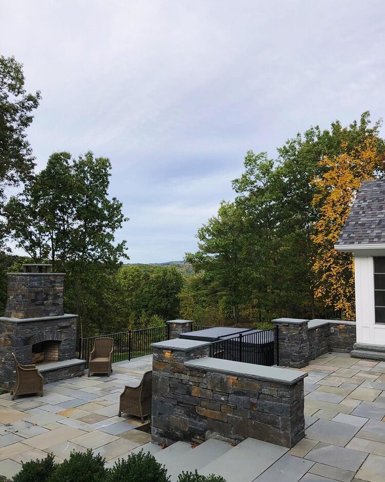 Design ideas for a contemporary back patio in New York with a fireplace, natural stone paving and no cover.