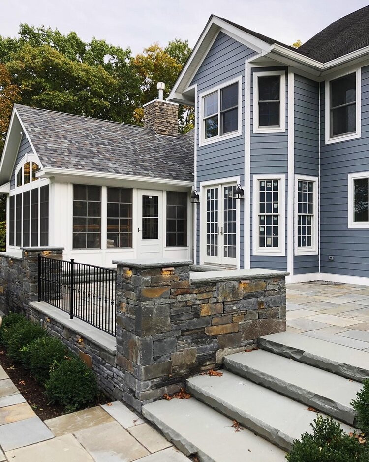 Immagine di un patio o portico design dietro casa con un caminetto, pavimentazioni in pietra naturale e nessuna copertura