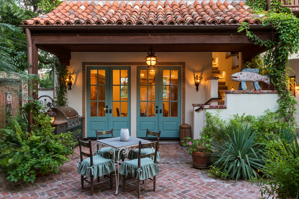 Esempio di un patio o portico mediterraneo di medie dimensioni e dietro casa con pavimentazioni in mattoni e un tetto a sbalzo