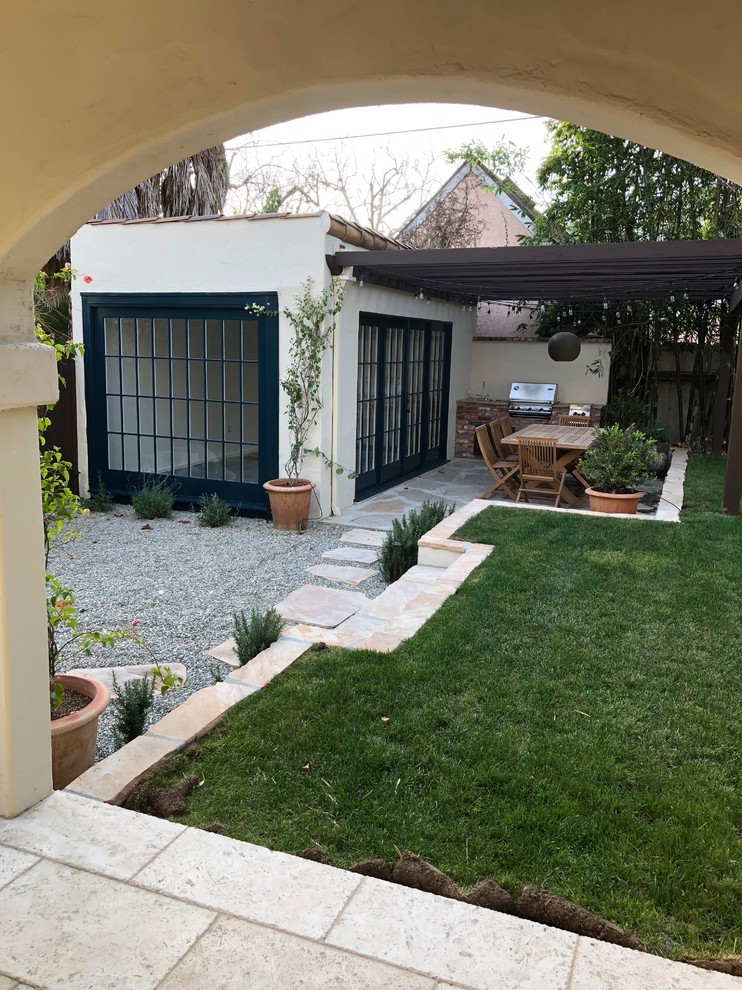 Photo of a medium sized back patio in Los Angeles with an outdoor kitchen, gravel and a pergola.