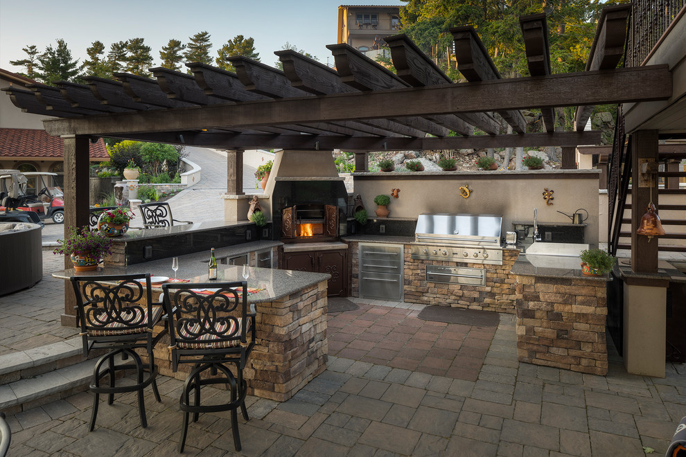 Expansive classic back patio in Toronto with an outdoor kitchen, natural stone paving and a pergola.