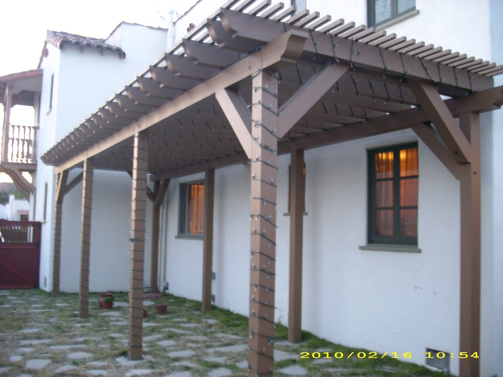 Example of a mid-sized tuscan side yard concrete paver patio design in Los Angeles with a pergola