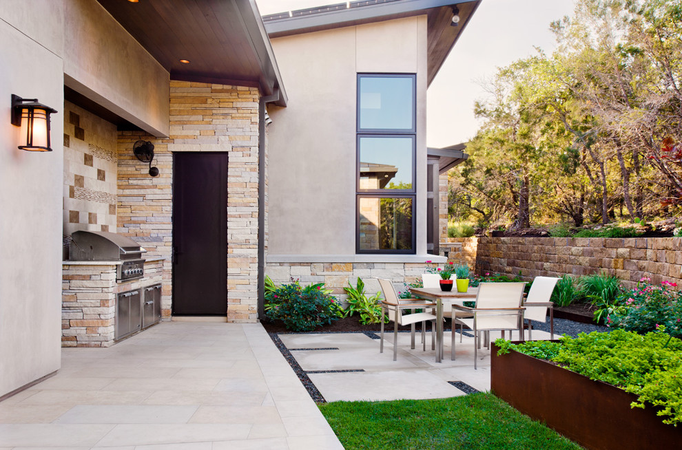Aménagement d'une terrasse arrière contemporaine de taille moyenne avec une cuisine d'été, une extension de toiture et des pavés en béton.