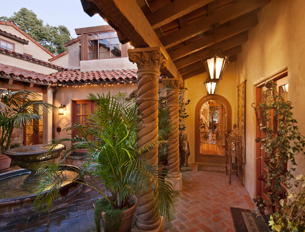 Photo of a medium sized mediterranean courtyard patio in Santa Barbara with a water feature, tiled flooring and a roof extension.