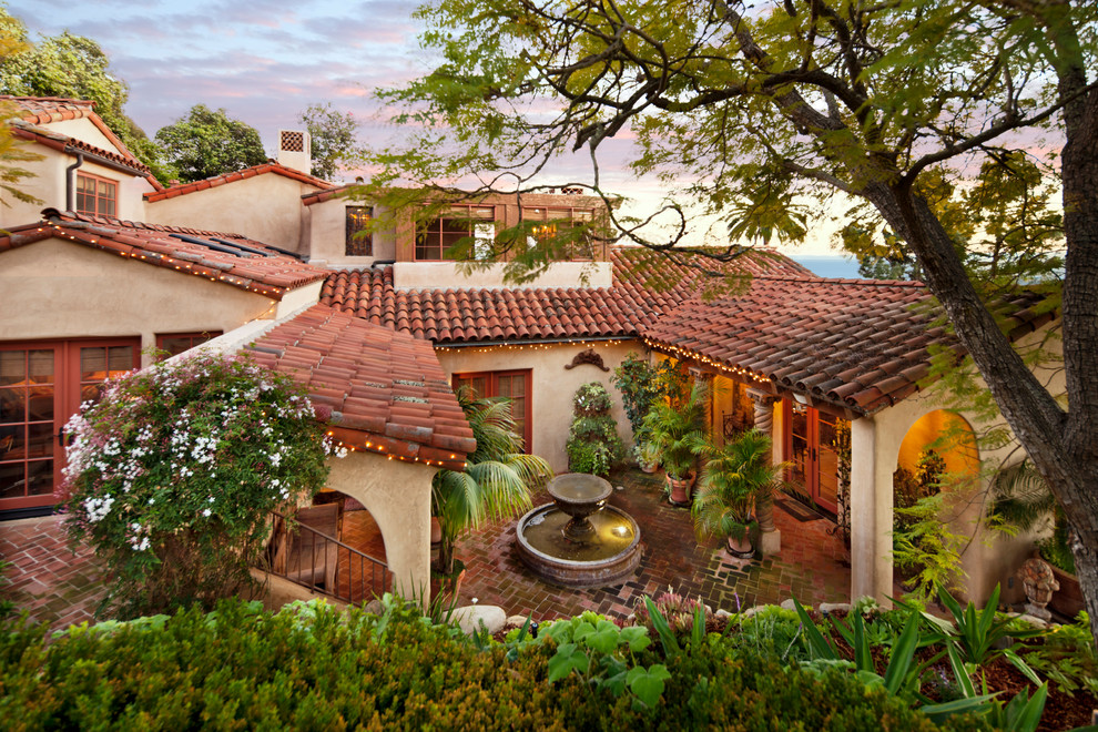 Mid-sized tuscan courtyard tile patio fountain photo in Santa Barbara with a roof extension
