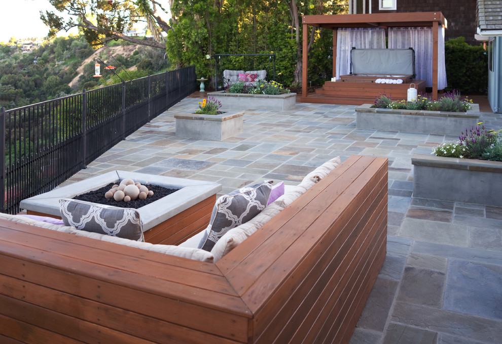 Cette image montre une terrasse arrière design de taille moyenne avec un foyer extérieur et des pavés en pierre naturelle.