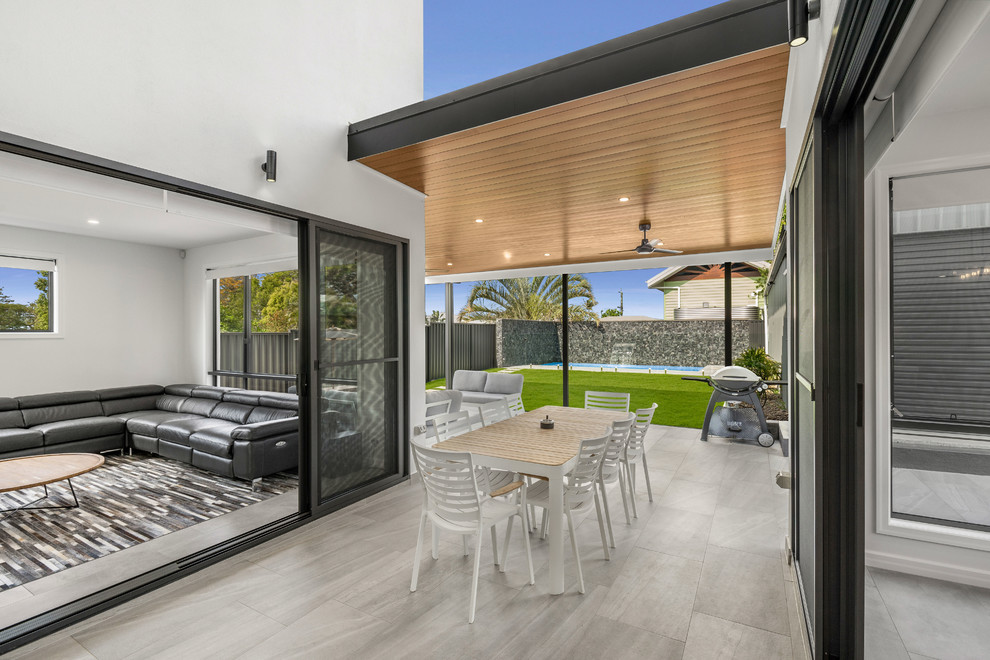 Photo of a large contemporary back patio in Brisbane with tiled flooring and a roof extension.