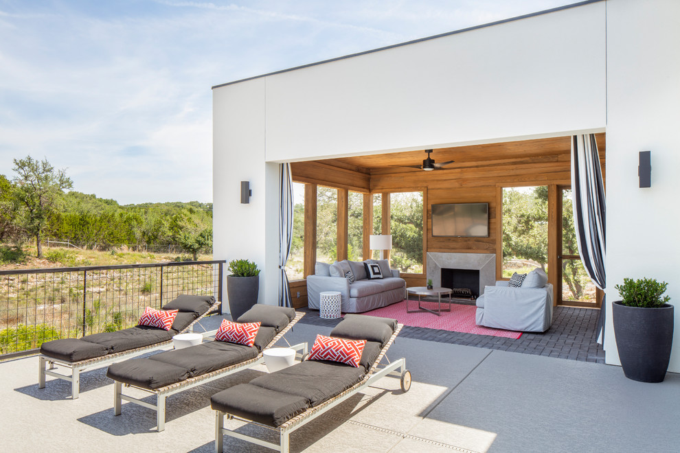 Photo of a large contemporary back patio in Austin with a fire feature, concrete paving and a roof extension.