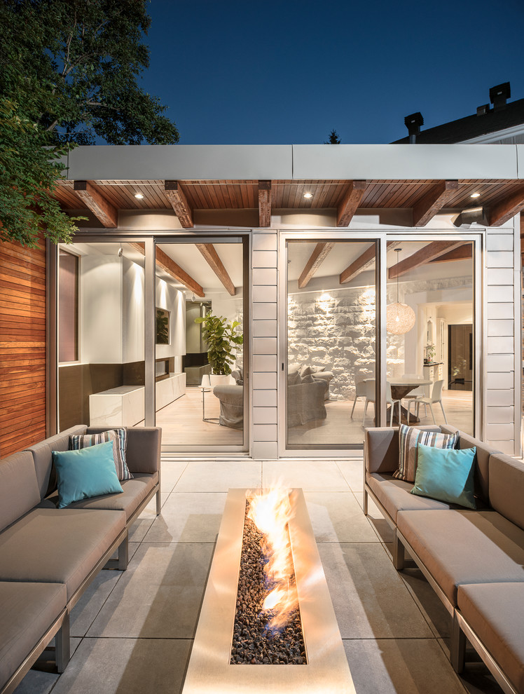 Cette image montre une terrasse design avec un foyer extérieur, une dalle de béton et aucune couverture.