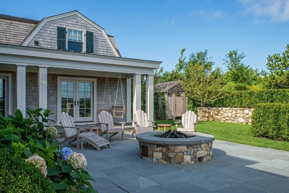 Cette photo montre une terrasse arrière nature de taille moyenne avec un foyer extérieur, des pavés en béton et une extension de toiture.