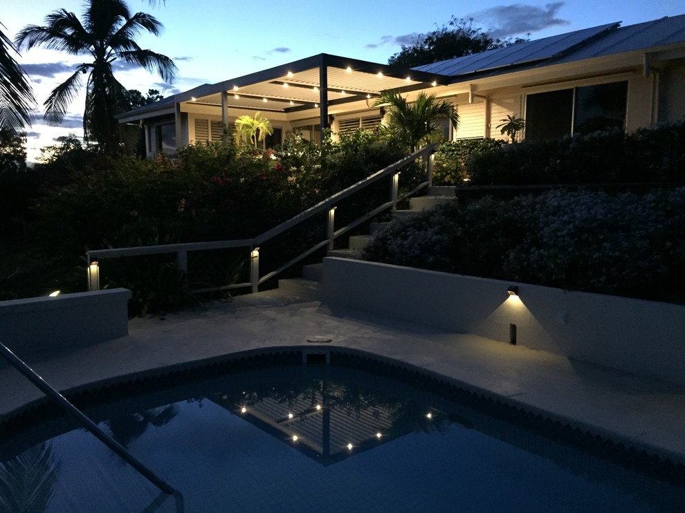 Immagine di un patio o portico tropicale dietro casa e di medie dimensioni con una pergola, fontane e lastre di cemento