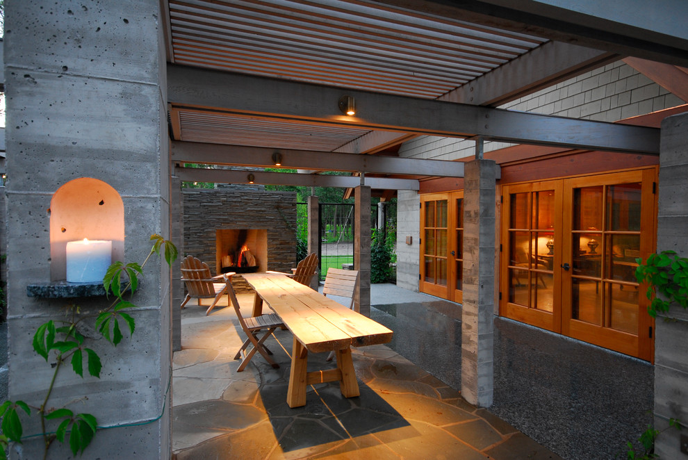 Cette image montre une très grande terrasse arrière minimaliste avec un foyer extérieur, une pergola et un gravier de granite.