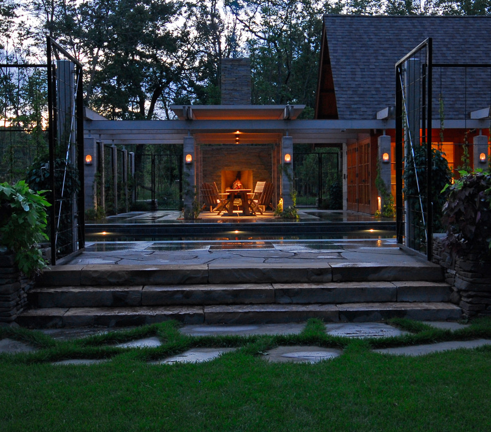Foto di un ampio patio o portico minimalista dietro casa con un focolare, pavimentazioni in pietra naturale e una pergola