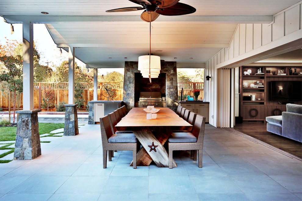 Réalisation d'une terrasse arrière chalet de taille moyenne avec une cuisine d'été, une dalle de béton et une extension de toiture.