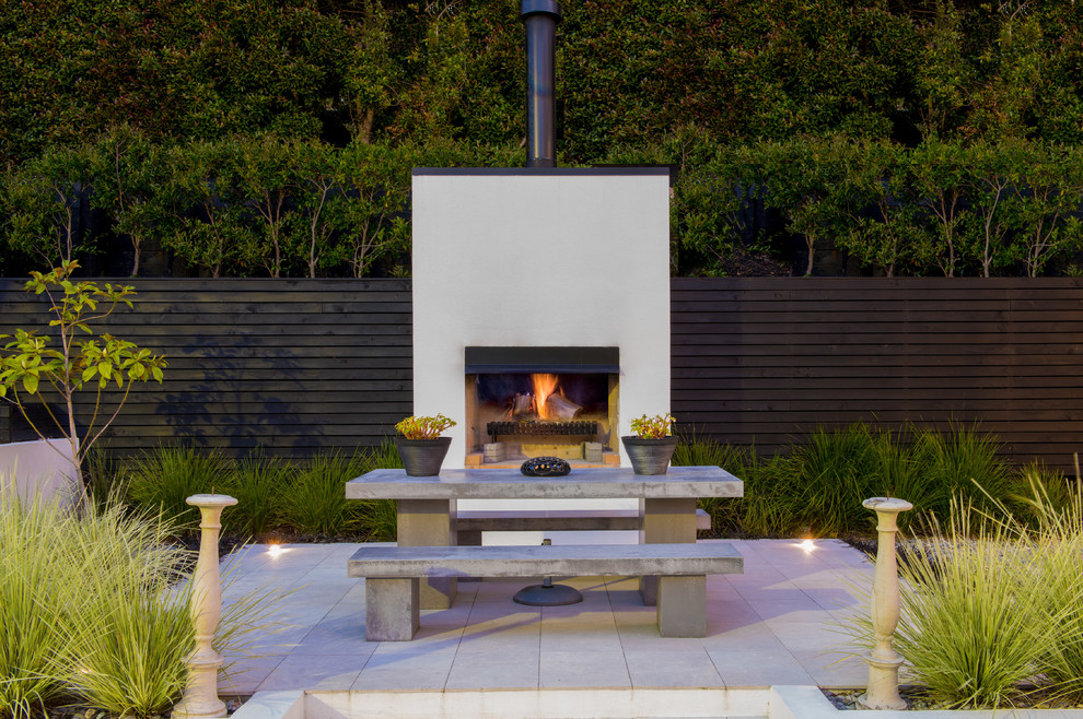 オークランドにある高級な広いコンテンポラリースタイルのおしゃれな裏庭のテラス (日よけなし、タイル敷き、屋外暖炉) の写真