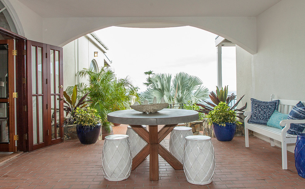 Esempio di un patio o portico tropicale di medie dimensioni e dietro casa con pavimentazioni in mattoni e un tetto a sbalzo