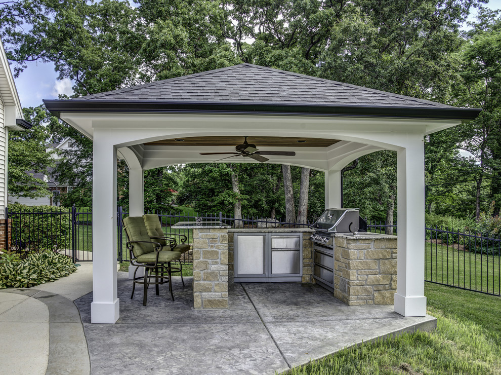 Elegant backyard stamped concrete patio kitchen photo in St Louis with a roof extension