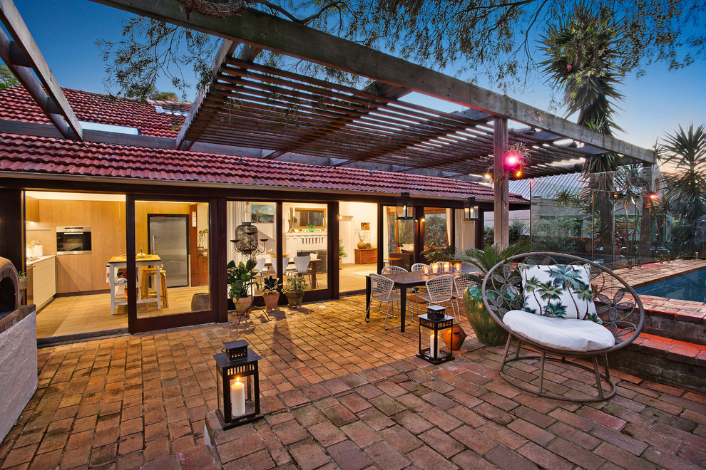 Inspiration for a medium sized contemporary back patio in Sydney with brick paving, a water feature and a pergola.