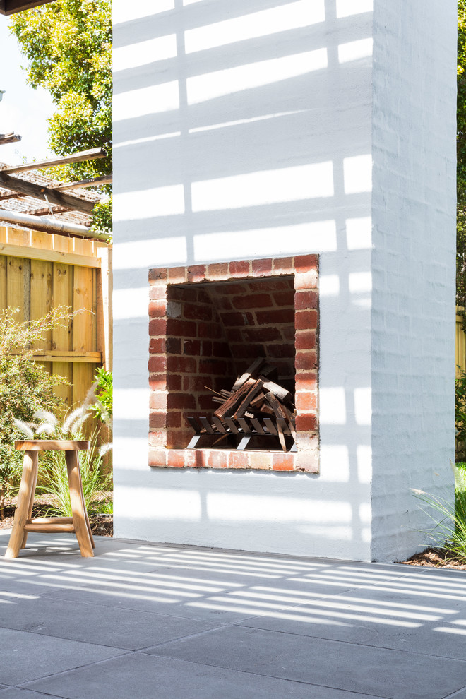メルボルンにある高級な中くらいなコンテンポラリースタイルのおしゃれな裏庭のテラス (屋外暖炉、天然石敷き、パーゴラ) の写真