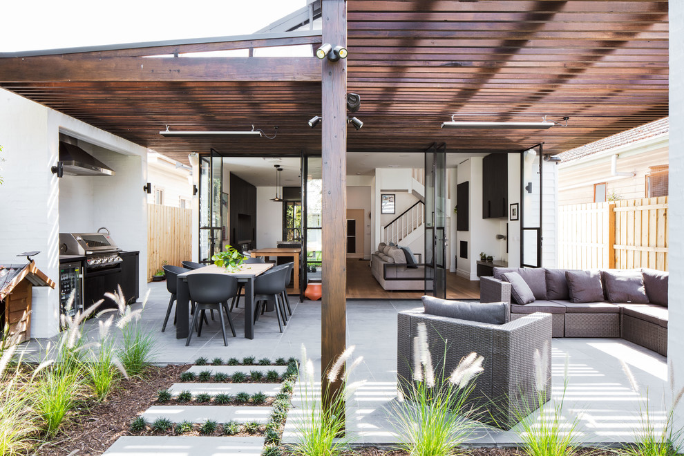 Diseño de patio actual de tamaño medio en patio trasero con chimenea, adoquines de piedra natural y pérgola