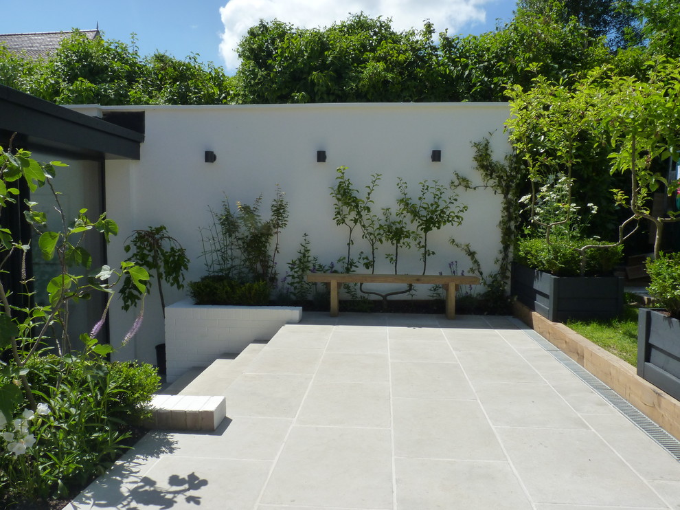 Large contemporary back patio in Berkshire with natural stone paving and no cover.
