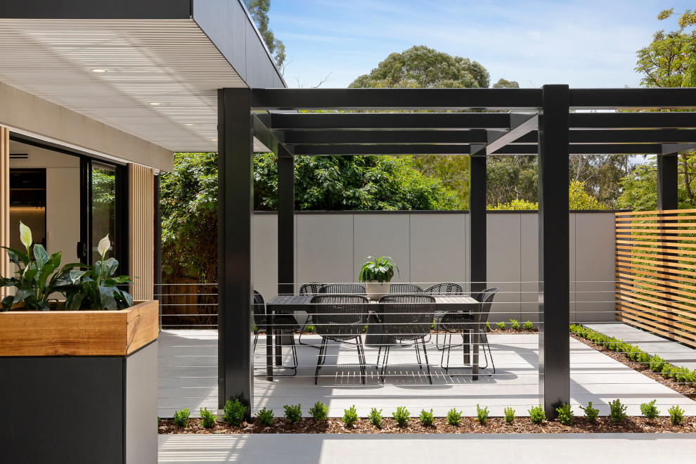 This is an example of a medium sized contemporary back patio in Melbourne with tiled flooring and a pergola.