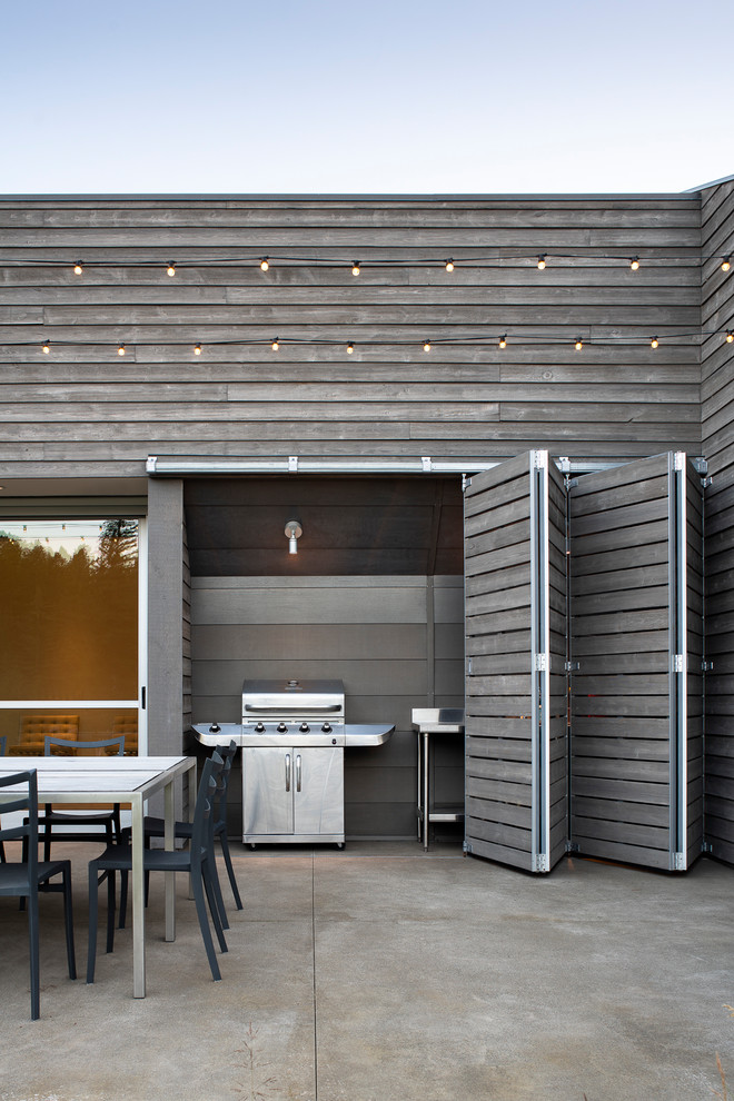 Foto de patio actual de tamaño medio sin cubierta en patio trasero con cocina exterior y losas de hormigón