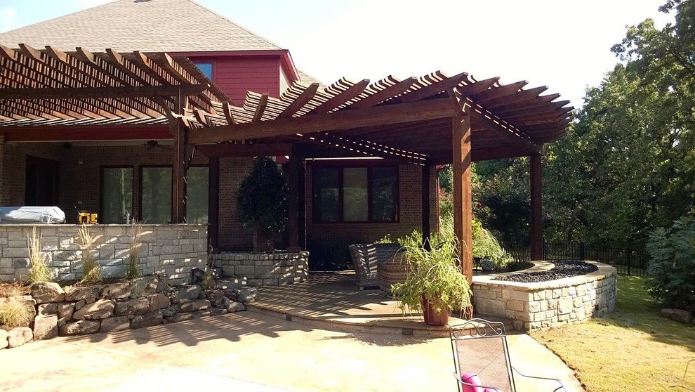 Foto di un grande patio o portico rustico dietro casa con cemento stampato e una pergola