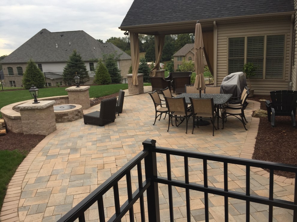 Large transitional backyard brick patio photo in Other with a fire pit and a roof extension