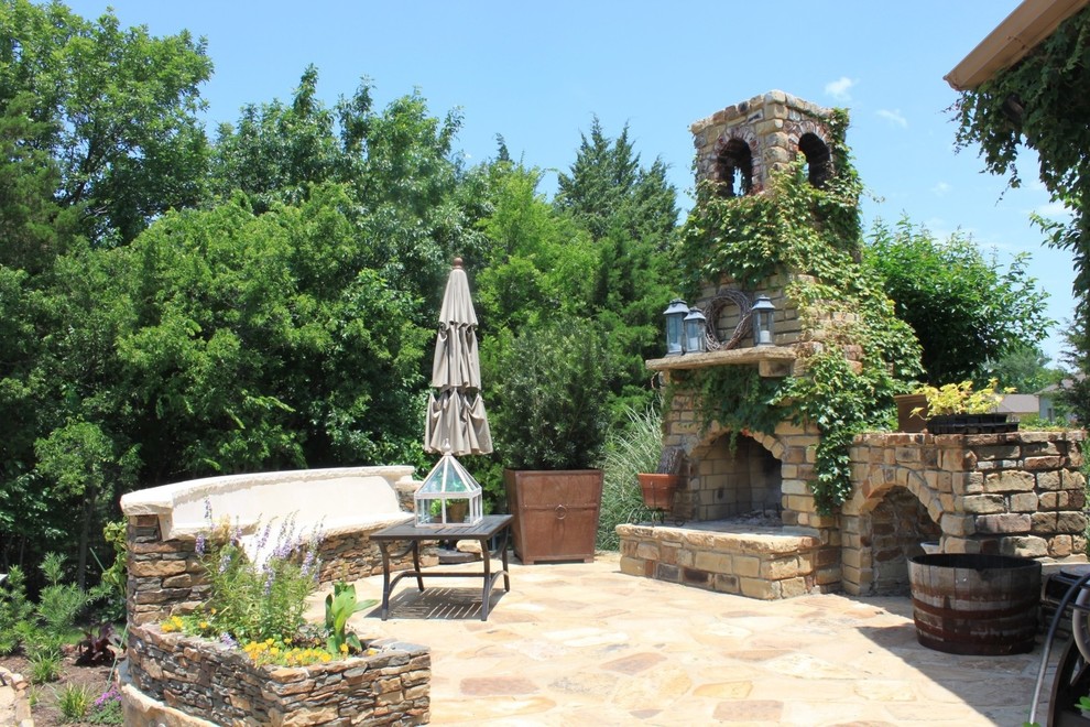 Inspiration for a mediterranean back patio in Dallas with an outdoor kitchen, natural stone paving and a roof extension.