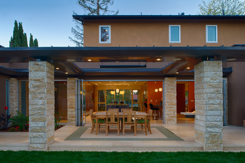 Foto di un grande patio o portico minimalista dietro casa con un focolare, piastrelle e un tetto a sbalzo