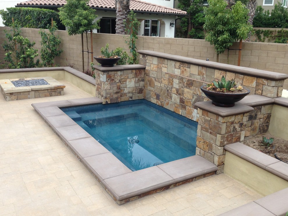 Diseño de piscina con fuente tradicional renovada de tamaño medio en patio trasero con adoquines de piedra natural