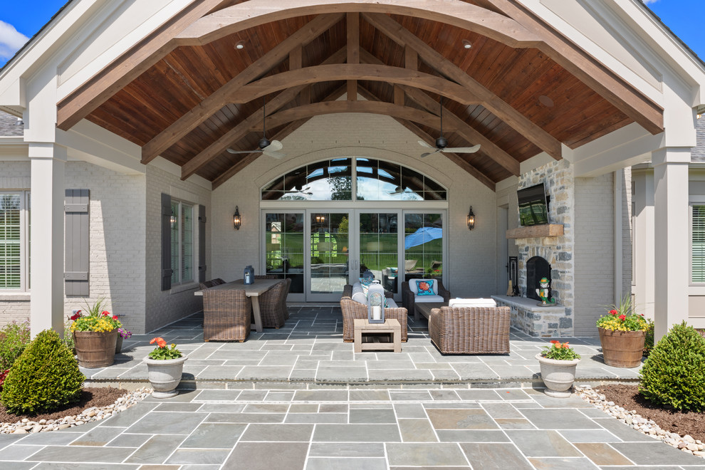 Пример оригинального дизайна: большой двор на заднем дворе в классическом стиле с уличным камином, покрытием из каменной брусчатки и навесом