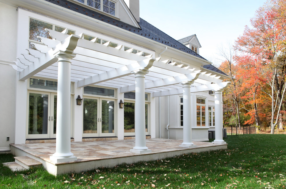 Example of a huge classic backyard stone patio design in Other with a pergola